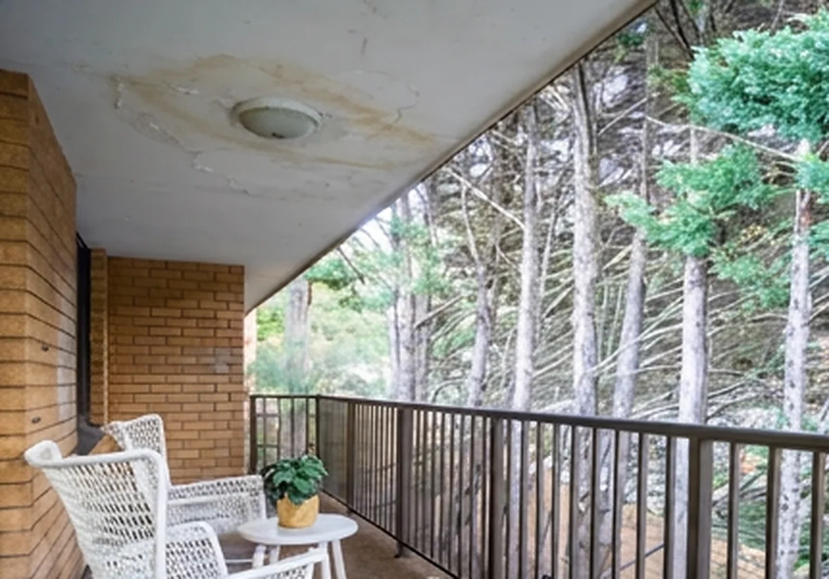An older balcony ceiling with cracking and brown staining spreading from the light fitting, seen from the deck.