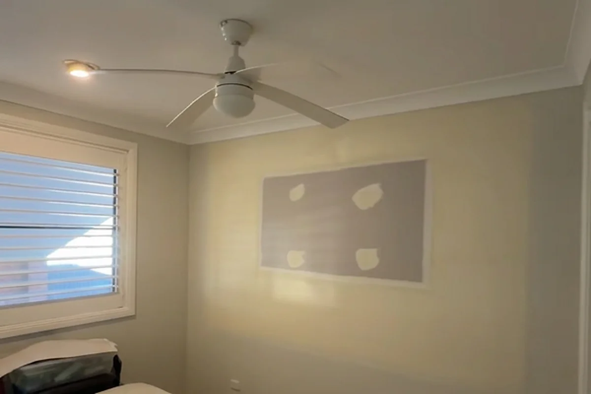 A wide patch of setting compound spread across a bedroom wall, with the sanded edges feathered out into the paint.