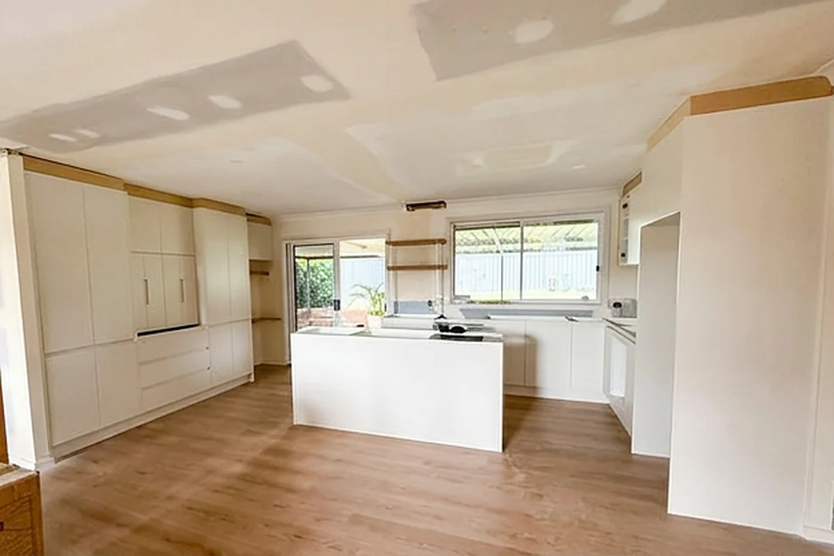 A finished kitchen and living area with the ceiling replaced and set, ready for painting above the joinery.