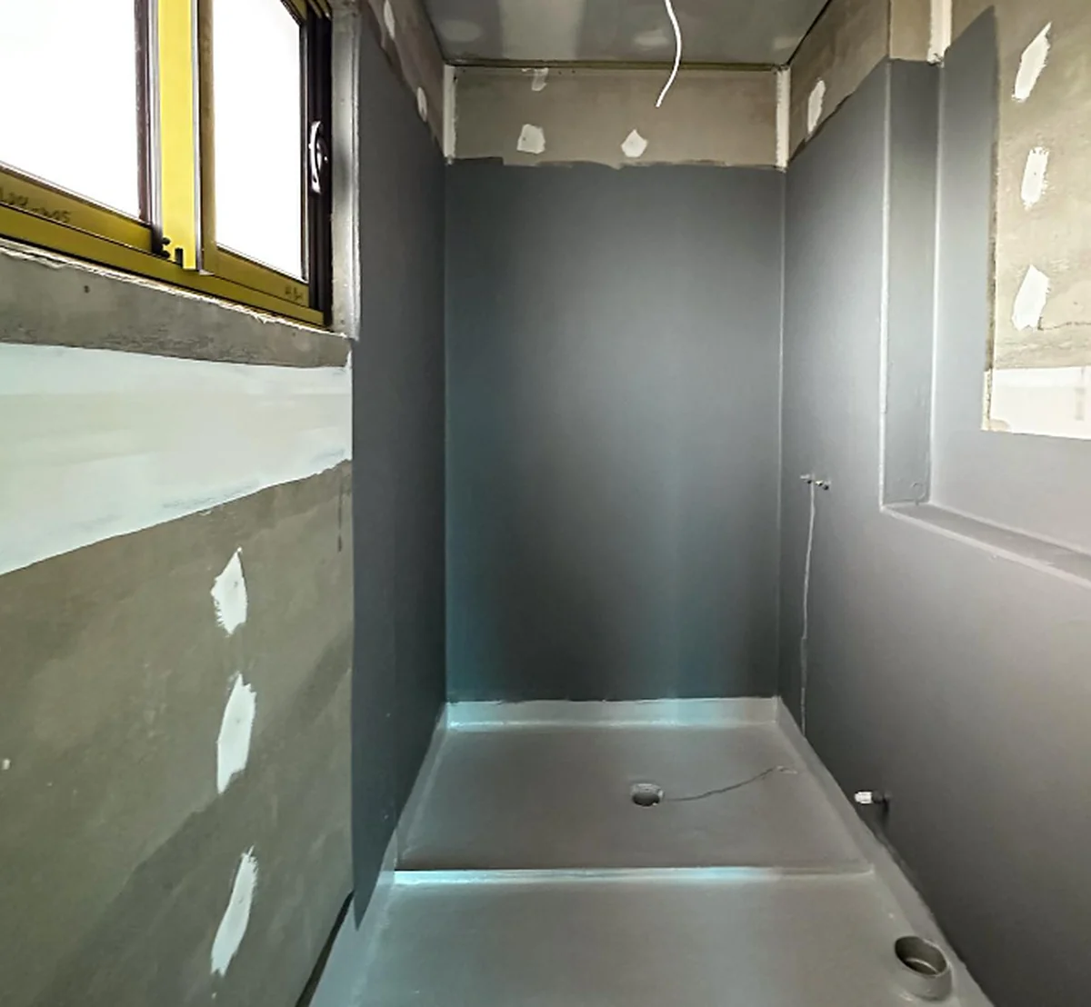 A bathroom lined and set ready for tiling, with the joints run around the bath recess and the sheets sealed.